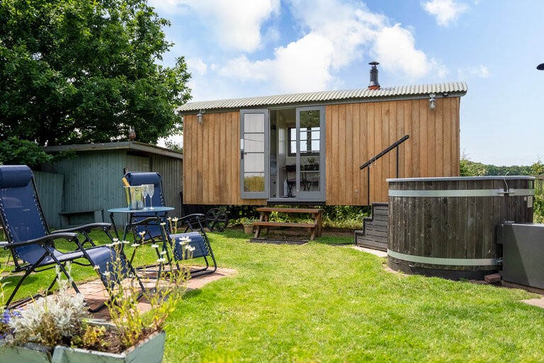 The shepherds hut benefits from a hot tub, reclining chairs, a bistro table, bbq and fire pit